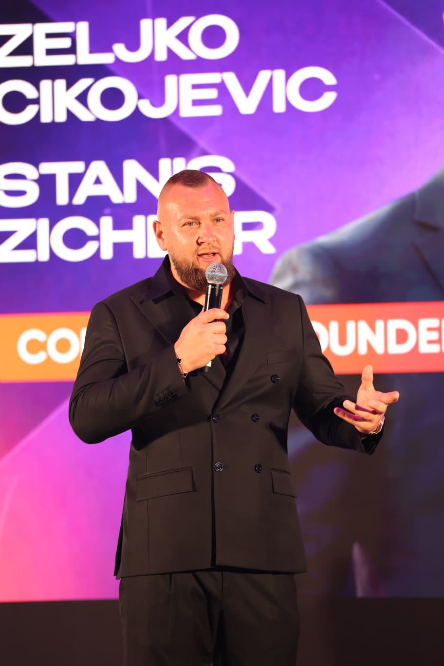 Stanis Zichler speaking on stage at a community event